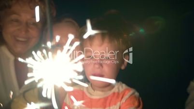 Parents, child and sparkler at night