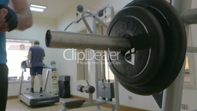 Sportsman putting disk weight on the barbell in gym