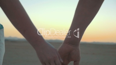 Loving couple holding hands at sunset