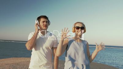 Young people in headphones relaxing on beach
