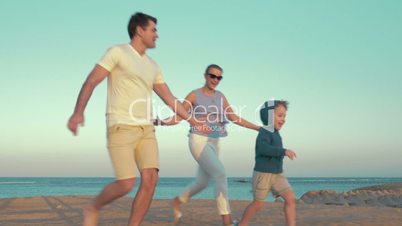 Happy family of three playing on the beach