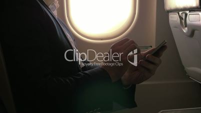 Man using pen to type on smart phone in plane