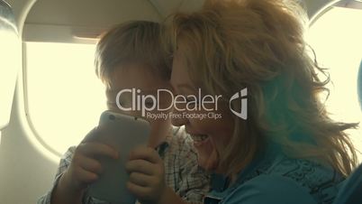 Child and grandmother entertaining with phone in plane