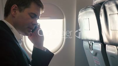 Young man having a business phone talk in plane