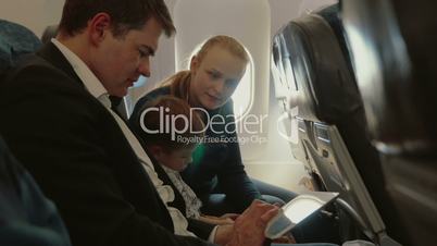 Family of three in plane with smartphone and tablet PC