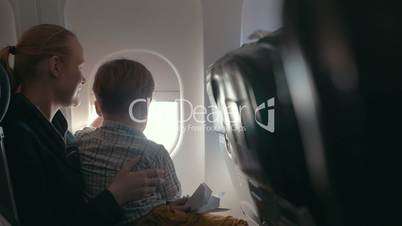 Boy and mother looking outside through plane window