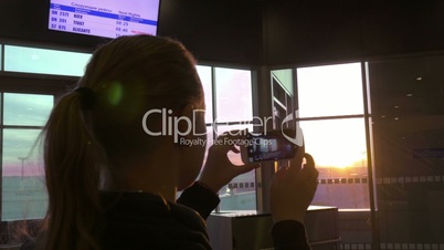 Woman making sunset photos with cell