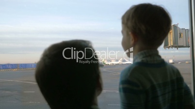 Father and son looking out the window at airport