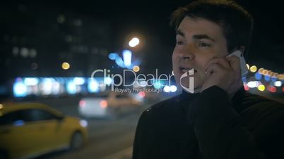 Man having phone conversation outdoor in night city