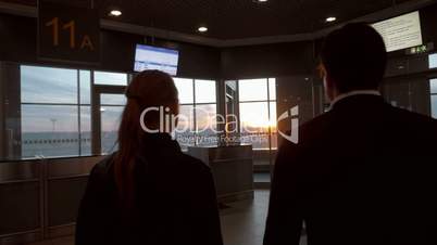 Man and woman enjoying sunset through airport window