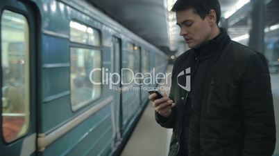 Man typing sms standing on the subway platform