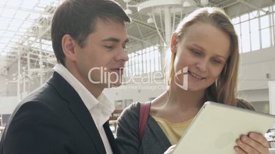 Young happy man and woman talking on business with pad