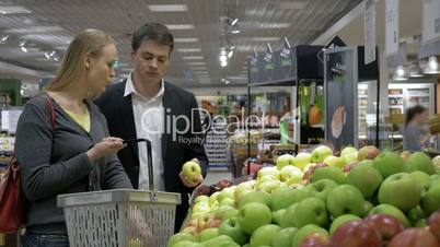 Young people choosing apples in the supermarket