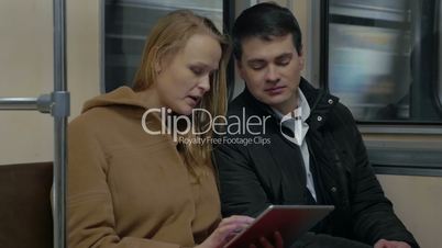 Young people using tablet computer in moving subway train