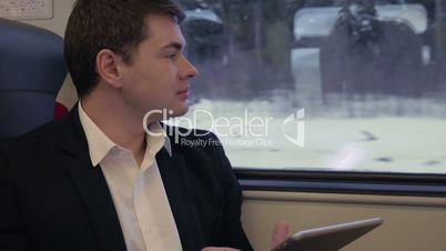 Young businessman working with pad in the train