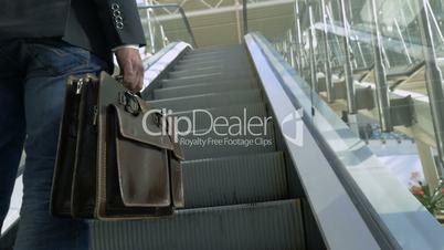 Businessman with leather briefcase riding on escalator