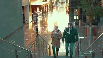 Young couple with pad going upstairs in modern trade centre