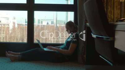 Woman uisng laptop by the window in hotel room