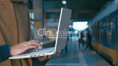 Girl working with laptop at the railway station