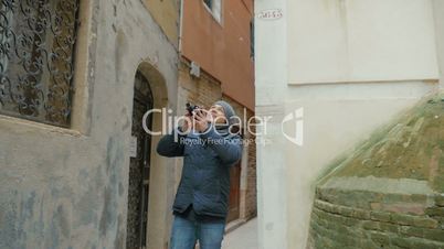 Man filming old architecture with retro camera