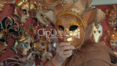 Woman in the store trying on golden Venetian mask
