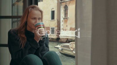 Wistful woman having coffee at home in Venice