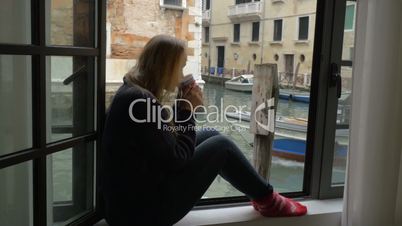 Woman with tea enjoying scene from the window