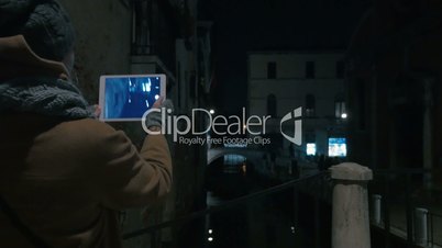 Woman with pad taking shots of Venice canal at night