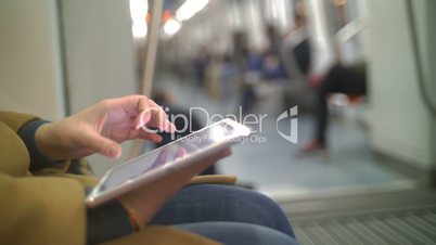 Woman in subway train using tablet PC