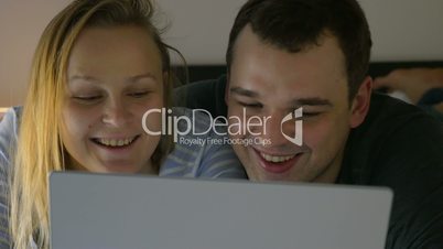 Couple watching humorous video on laptop