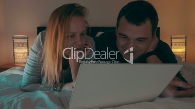 Couple in bed watching movie on laptop