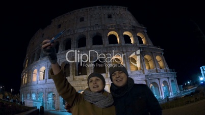 Selfie of tourists against Coliseum at night