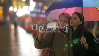 Female friends making selfie under rainbow umbrella