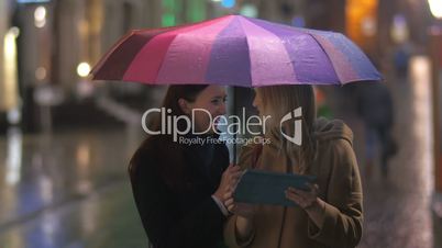 Female Friends with Tablet under an Umbrella