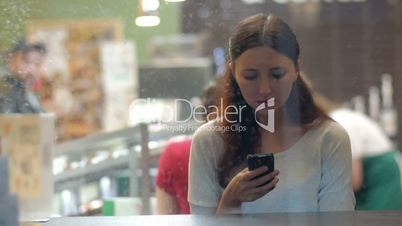 Woman exchanging messages on cell in cafe