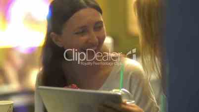 Women friends using tablet PC and eating cake in cafe