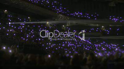 Crowd on stands waving flashlights at night