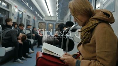 Young woman reading a book in subway