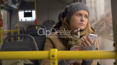 Young sad woman using smart phone in the bus