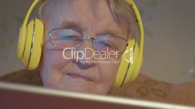 Senior woman in headphones using tablet computer