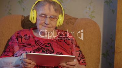 Modern Grandmother with Tablet PC and Headphones
