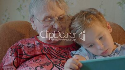 Boy Showing Something in Tablet to his Grandmother