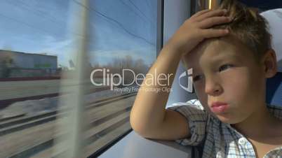Little boy looking out train window on sunny day