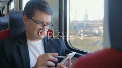 Young man using cell to browse online in train