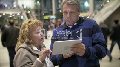 Mature Couple with Tablet PC in Public Place