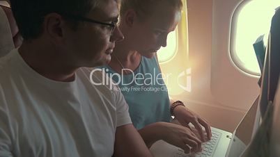 Young people working with laptop in plane
