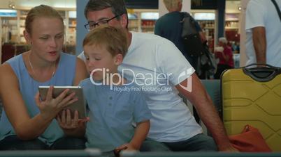 Parents and child using digital tablet at the airport