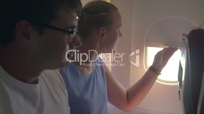 Woman and man looking out plane window