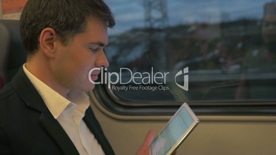 Man in Train Laughing at Tablet