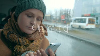 Woman using phone in bus on rainy day